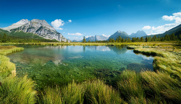 Original photo: a clear mountain lake in a grassy meadow under a blue sky